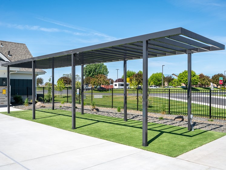 A bus stop shelter with a metal frame and a roof is located on a sidewalk.